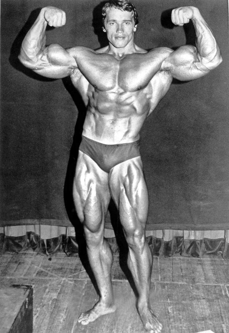 Egy egészalakos fotó Arnold Schwarzeneggeről ahol éppen egy testépítő pózt vesz fel.