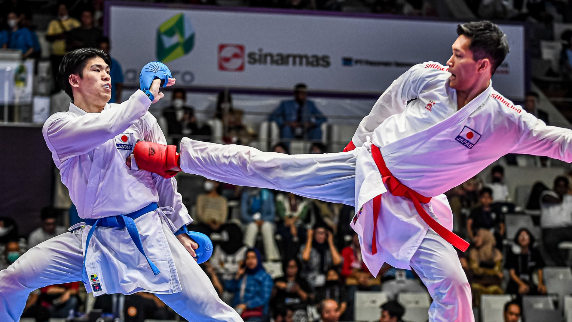 The competitor in red protection gear throws a right side kick which connects.