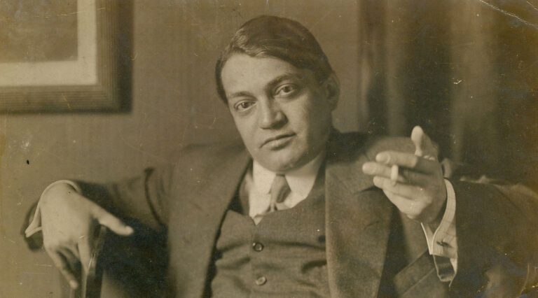 Ady Endre öltönyben cigarettázva ül egy falnál