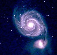 A bright spiral galaxy (Messier 51 - Whirlpool Galaxy) with well-defined arms glowing in shades of blue and white