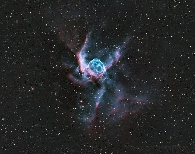 A shot of a colourful nebula with a beautiful blue and dark purple tint, with hundreds of stars visible in the background.