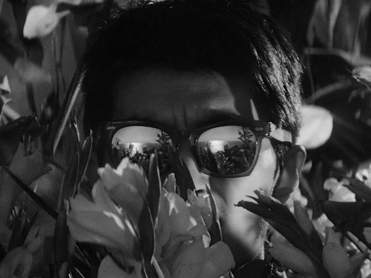 Scene from 'High and Low', where a man is wearing a sunglass hiding in a bush