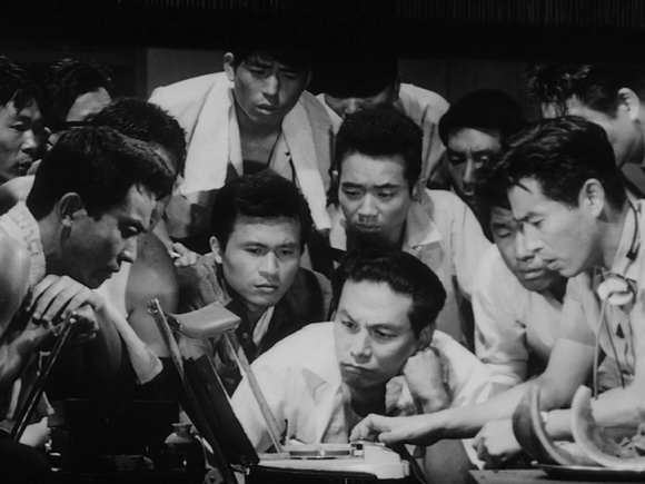 Scene from 'High and Low', where a lot of people are looking at a desk