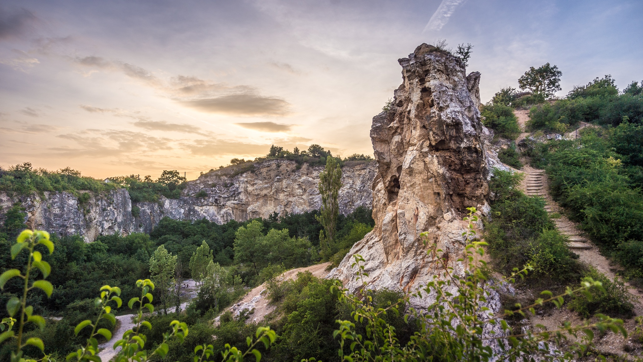 Panorámakép a Rókahegyről, a sziklamászó rész bejáratától fotózva. A burjánzó zöld növényzetből gyönyörű sziklák magasodnak ki körben.