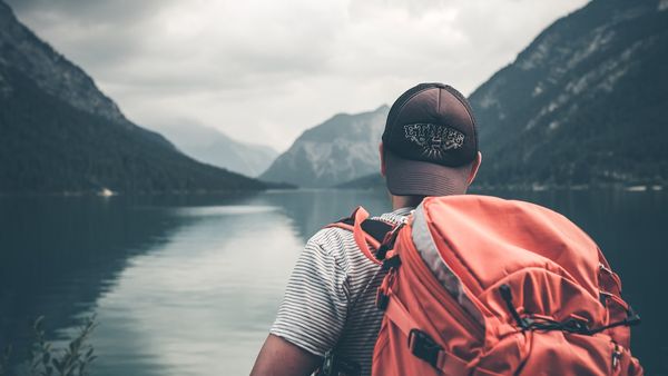 Egy turista áll egy hegyi tó előtt.